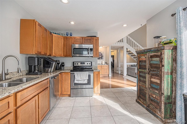 kitchen featuring light tile patterned flooring, recessed lighting, a sink, appliances with stainless steel finishes, and light stone countertops