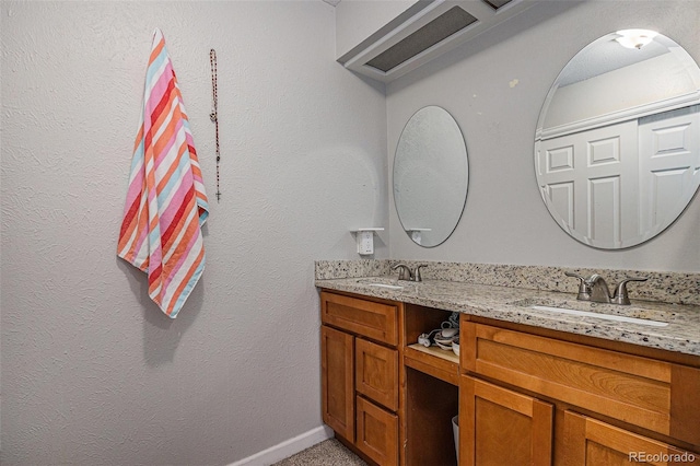 bathroom featuring double vanity, a sink, and baseboards