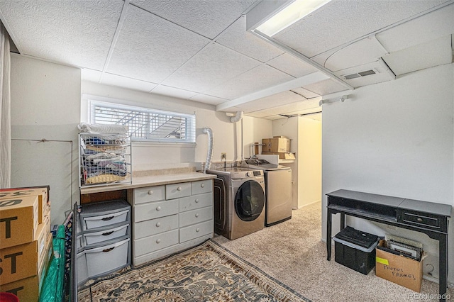 clothes washing area featuring washing machine and dryer, visible vents, and carpet