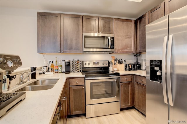 kitchen featuring light wood finished floors, appliances with stainless steel finishes, and a sink