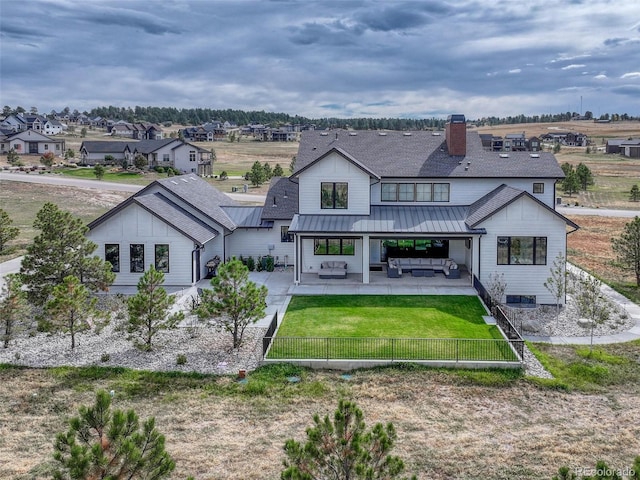 rear view of house with a patio area, an outdoor living space, a yard, and a fenced front yard