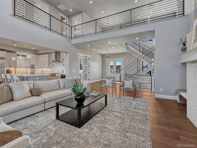 living room with baseboards, dark wood finished floors, a high ceiling, stairs, and french doors