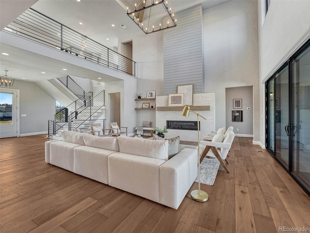 living room with stairway, a notable chandelier, baseboards, and wood-type flooring