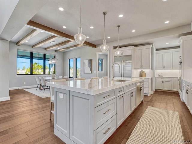 kitchen with a spacious island, dark wood-type flooring, white cabinets, stainless steel appliances, and a sink