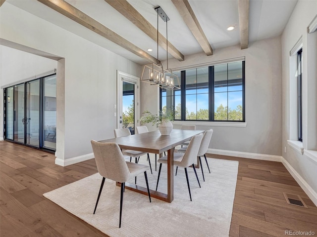 dining room featuring wood finished floors, baseboards, visible vents, and a chandelier