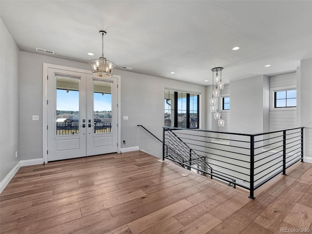 entrance foyer featuring visible vents, baseboards, a chandelier, french doors, and hardwood / wood-style flooring