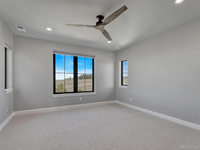 spare room featuring light carpet, ceiling fan, and baseboards