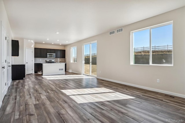 unfurnished living room featuring plenty of natural light and hardwood / wood-style floors