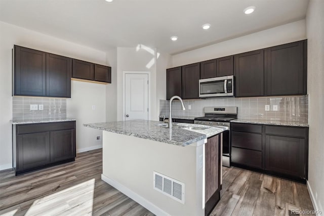 kitchen featuring dark brown cabinets, stainless steel appliances, a kitchen island with sink, and sink