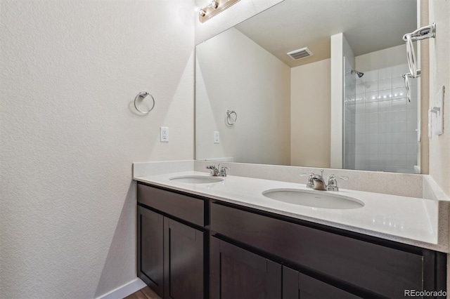 bathroom featuring a tile shower and vanity