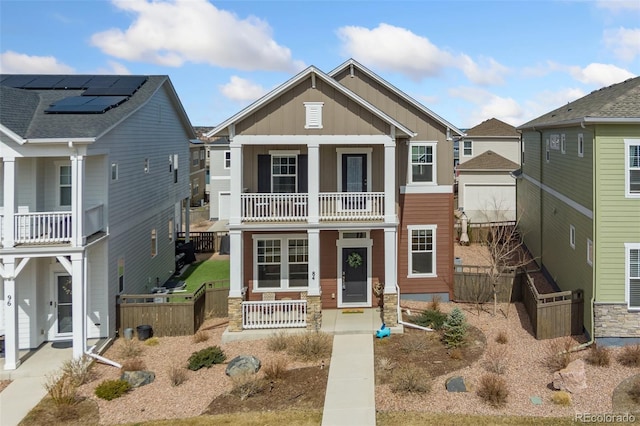 view of front of home featuring board and batten siding, a balcony, fence, and covered porch