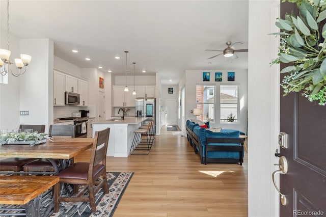 dining space featuring recessed lighting, light wood-type flooring, and ceiling fan with notable chandelier