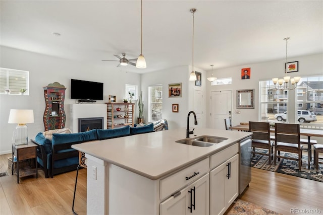 kitchen featuring a sink, stainless steel dishwasher, light wood-style flooring, and light countertops