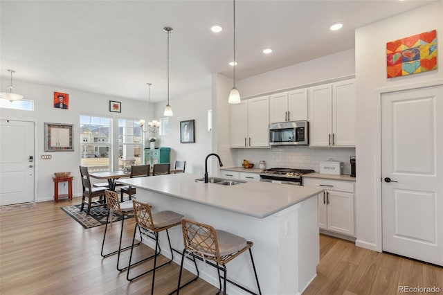 kitchen featuring a breakfast bar area, a sink, stainless steel appliances, light countertops, and backsplash