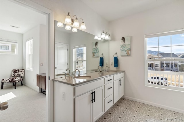 full bath with double vanity, baseboards, and a sink