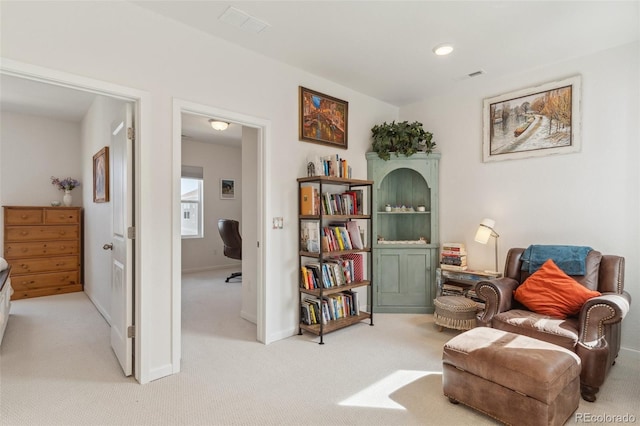 living area with visible vents, baseboards, and light colored carpet