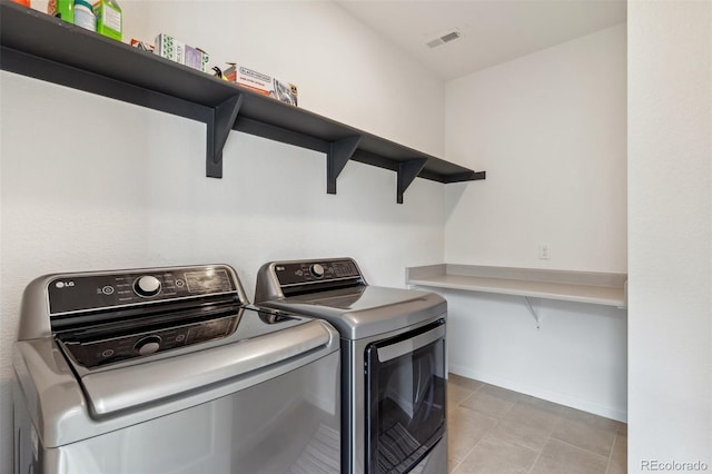 washroom with washer and clothes dryer, laundry area, visible vents, and light tile patterned flooring