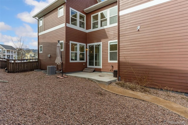 back of property with fence, central AC unit, and a patio area