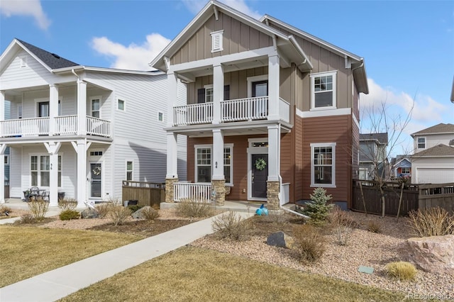 view of front of house featuring covered porch, board and batten siding, a balcony, and fence