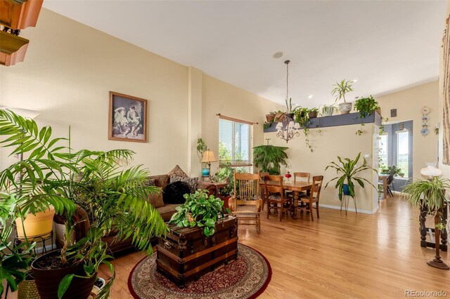 10554 Atwood Cir, Littleton, CO 80130 - living room with lofted ceiling, light wood-style flooring, baseboards, visible vents, and a chandelier