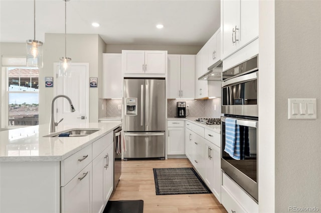 21426 E Stanford Ave, Aurora, CO 80015 - kitchen with stainless steel appliances, under cabinet range hood, tasteful backsplash, white cabinetry, and light stone countertops