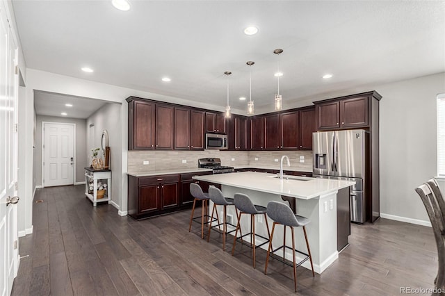 kitchen with pendant lighting, a kitchen breakfast bar, sink, an island with sink, and appliances with stainless steel finishes