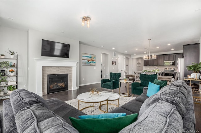 living room featuring dark hardwood / wood-style flooring, a tile fireplace, and a chandelier