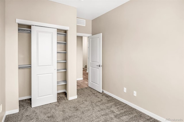 unfurnished bedroom with light colored carpet and a closet