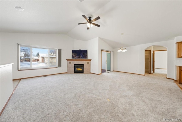 unfurnished living room featuring arched walkways, vaulted ceiling, light colored carpet, and a fireplace