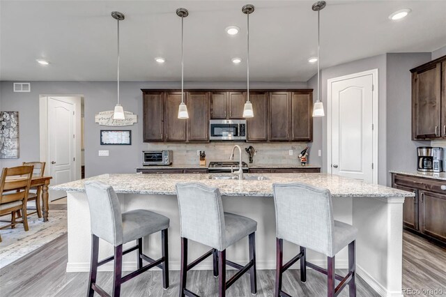 kitchen featuring dark brown cabinetry, stainless steel appliances, and light wood finished floors