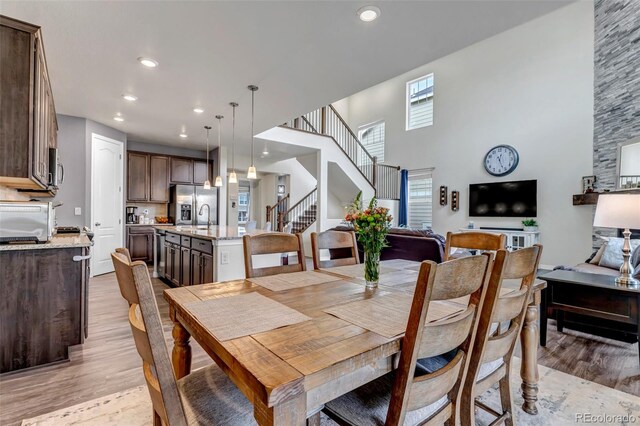 dining space with a towering ceiling, stairs, recessed lighting, light wood-type flooring, and a toaster