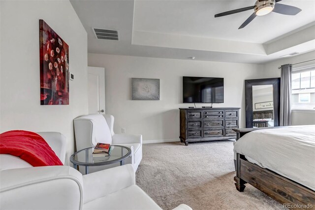 carpeted bedroom featuring visible vents, a raised ceiling, baseboards, and ceiling fan