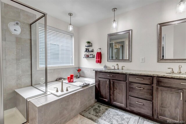 bathroom with double vanity, a shower stall, a sink, and a garden tub
