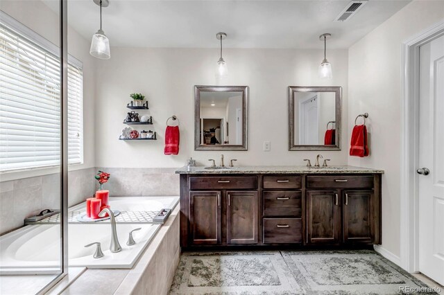 full bathroom featuring a sink, a bath, double vanity, and visible vents