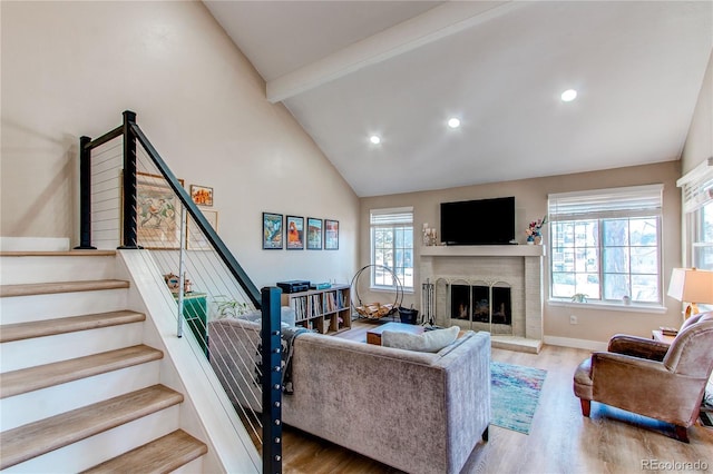 living room featuring stairs, a fireplace, wood finished floors, and beam ceiling