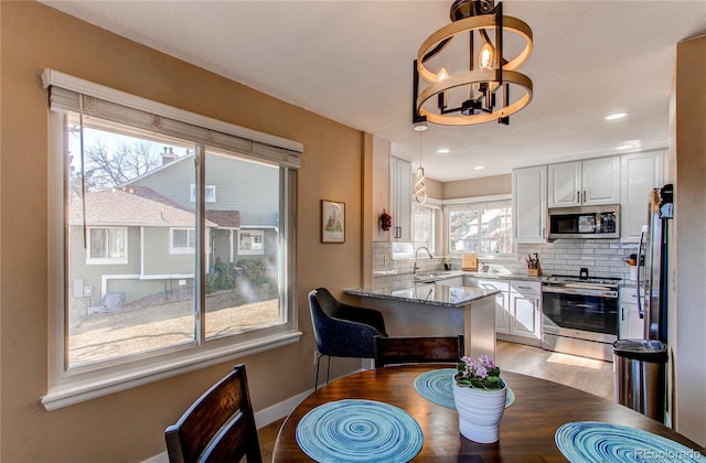 dining area with baseboards, light wood-style flooring, a chandelier, and recessed lighting