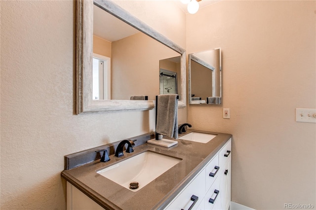 bathroom with double vanity, a sink, and a textured wall