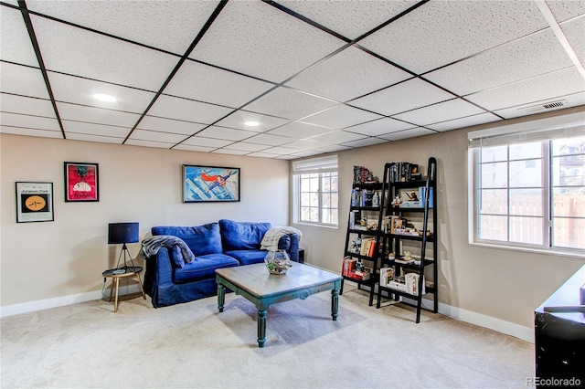 living room featuring carpet flooring, baseboards, and a drop ceiling