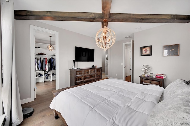 bedroom with hardwood / wood-style floors, beam ceiling, a notable chandelier, a spacious closet, and a closet