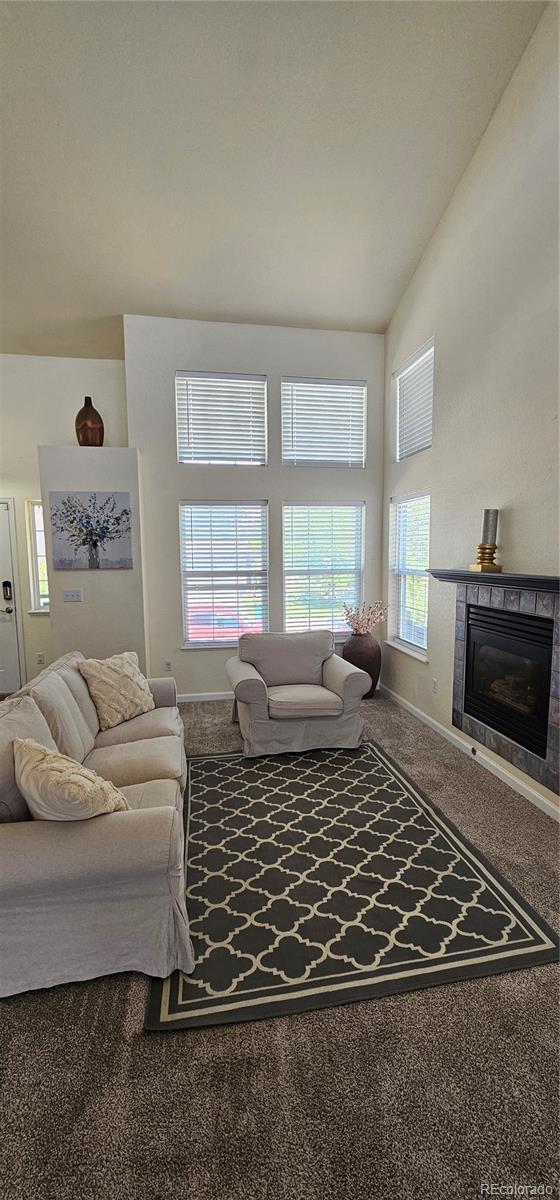 12388 Jasmine St, Brighton, CO 80602 - carpeted living area featuring a tile fireplace and lofted ceiling