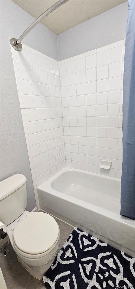 12388 Jasmine St, Brighton, CO 80602 - bathroom featuring shower / bath combination with curtain and tile patterned floors