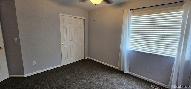 12388 Jasmine St, Brighton, CO 80602 - unfurnished bedroom with dark carpet, multiple windows, a closet, and a ceiling fan