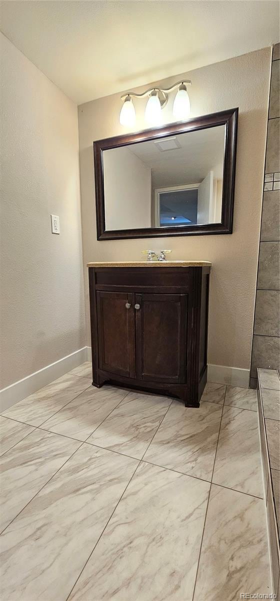 12388 Jasmine St, Brighton, CO 80602 - bathroom featuring marble look tiles and vanity