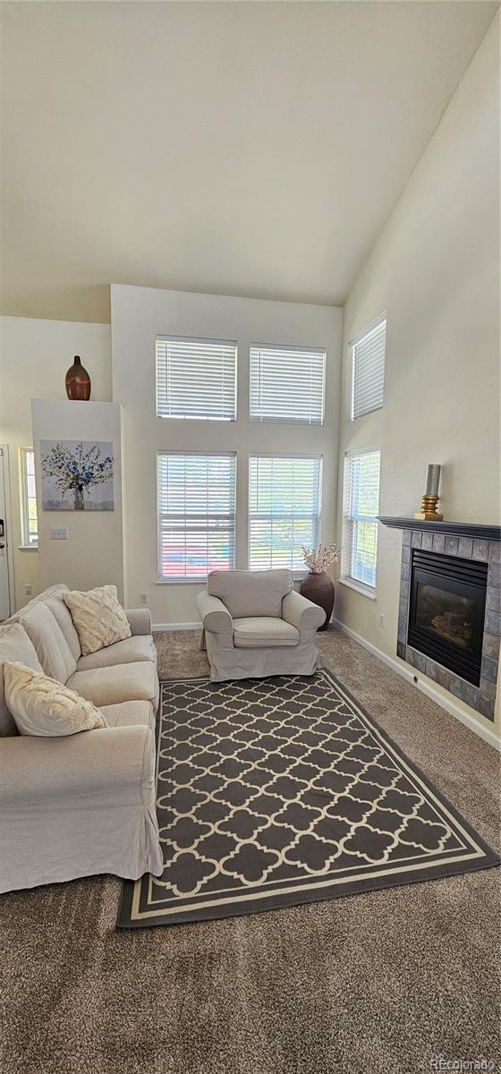 12388 Jasmine St, Brighton, CO 80602 - living room with healthy amount of natural light, carpet floors, a tile fireplace, and high vaulted ceiling