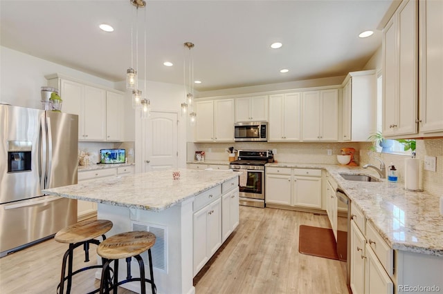 4863 Wildflower Pl, Dacono, CO 80514 - kitchen with appliances with stainless steel finishes, a kitchen island, tasteful backsplash, light wood-type flooring, and a kitchen breakfast bar