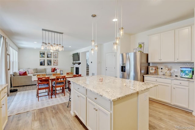 4863 Wildflower Pl, Dacono, CO 80514 - kitchen featuring stainless steel fridge, light wood finished floors, a center island, open floor plan, and hanging light fixtures
