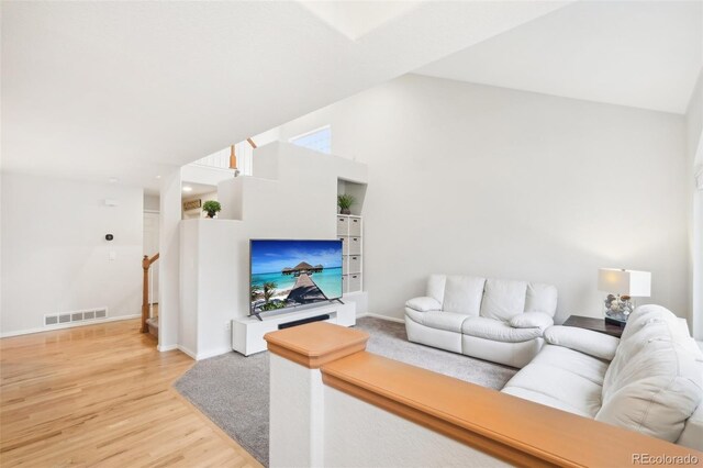 living room with light wood-style flooring, baseboards, and high vaulted ceiling