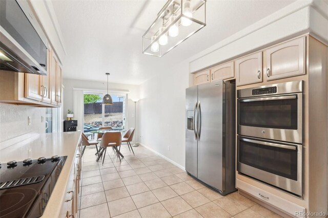 kitchen featuring appliances with stainless steel finishes, light tile patterned floors, light countertops, and hanging light fixtures