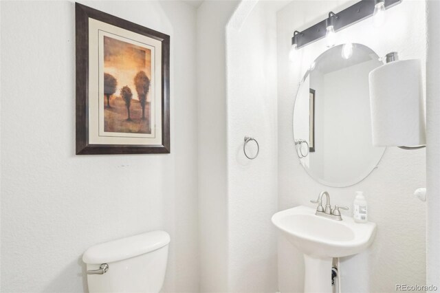 half bath featuring toilet and a sink