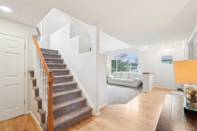 stairs featuring wood finished floors, baseboards, and arched walkways